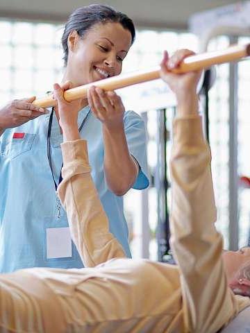 Nurse Helping Middle Aged Woman with Physical Therapy